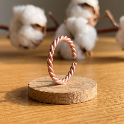 Ella's Twister twisted copper ring on a wooden disc