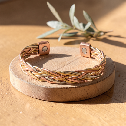Ella's Lucentia braided copper bracelet on a wooden disc