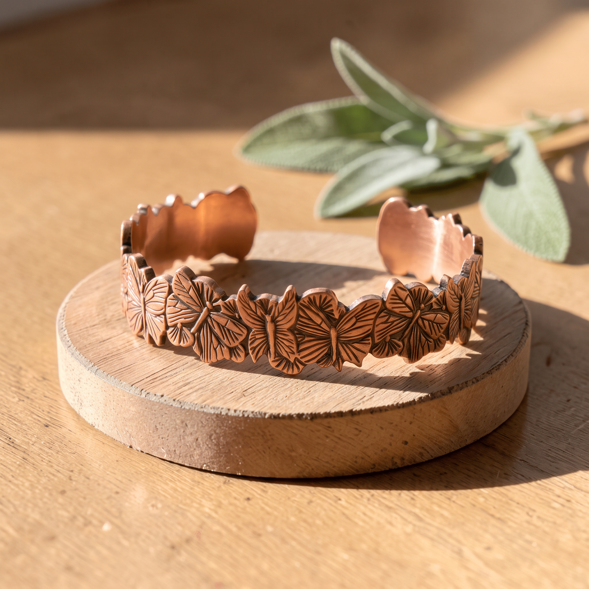Ella's Butterfly copper cuff on a wooden disc