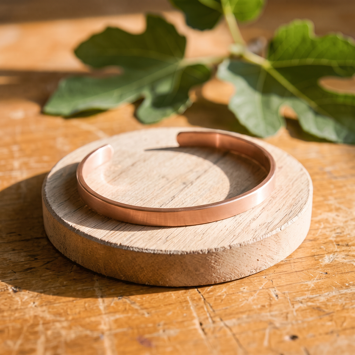 Ella's Frost solid copper cuff on a wooden disc