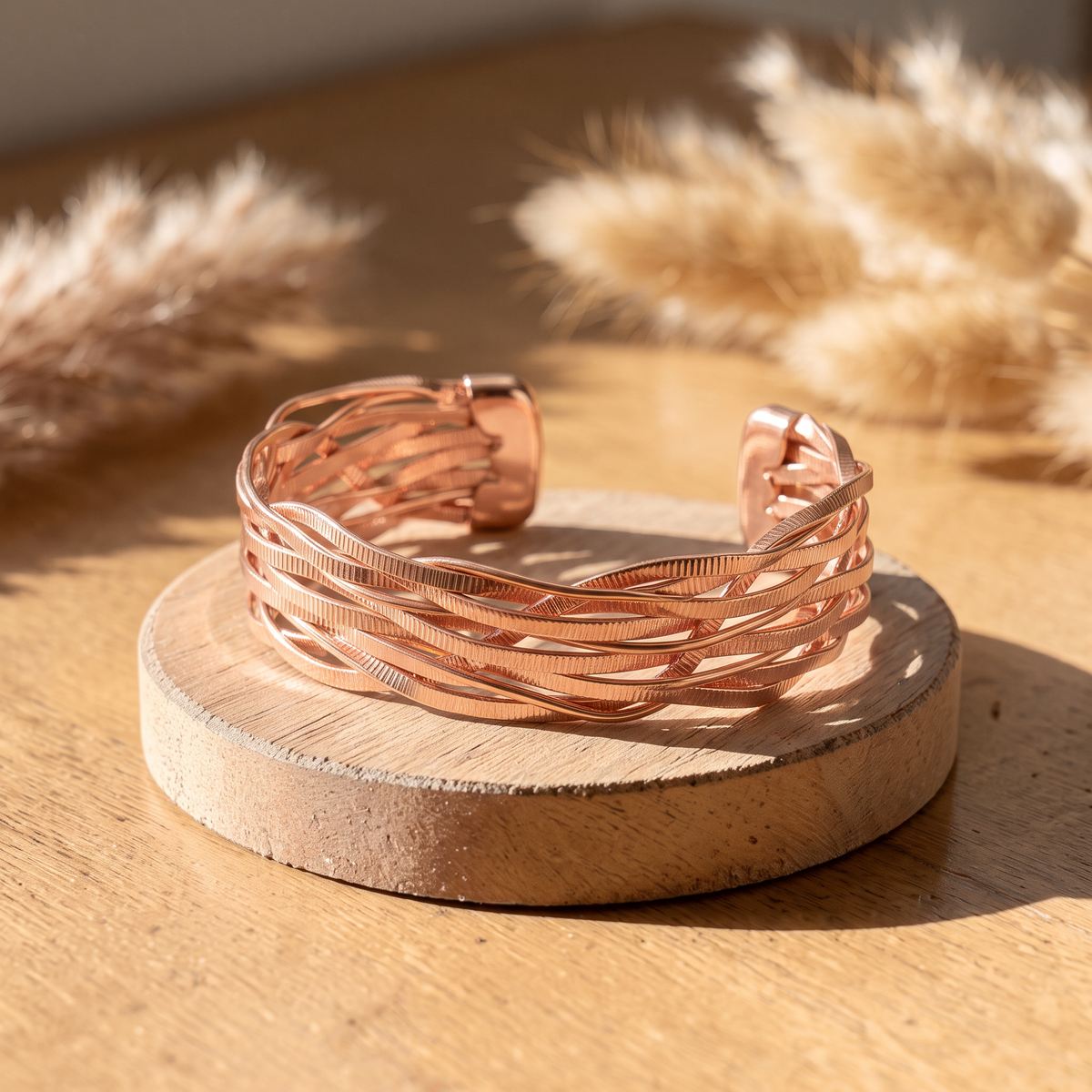 Ella's Wind woven copper cuff on a wooden disc