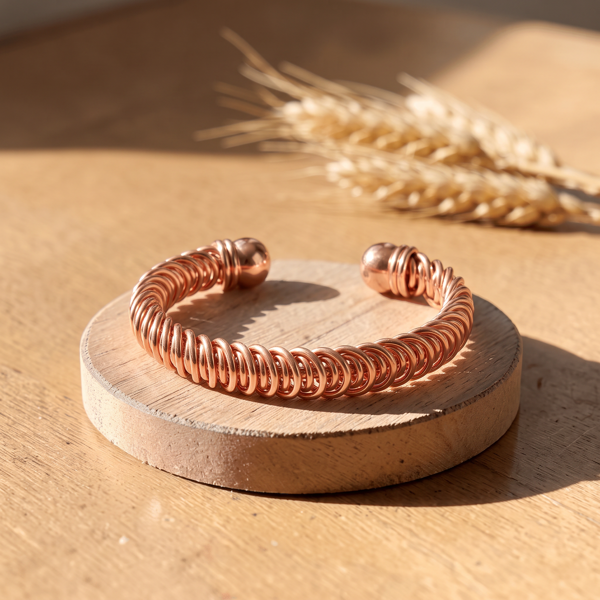Ella's Calista coiled copper cuff on a wooden disc