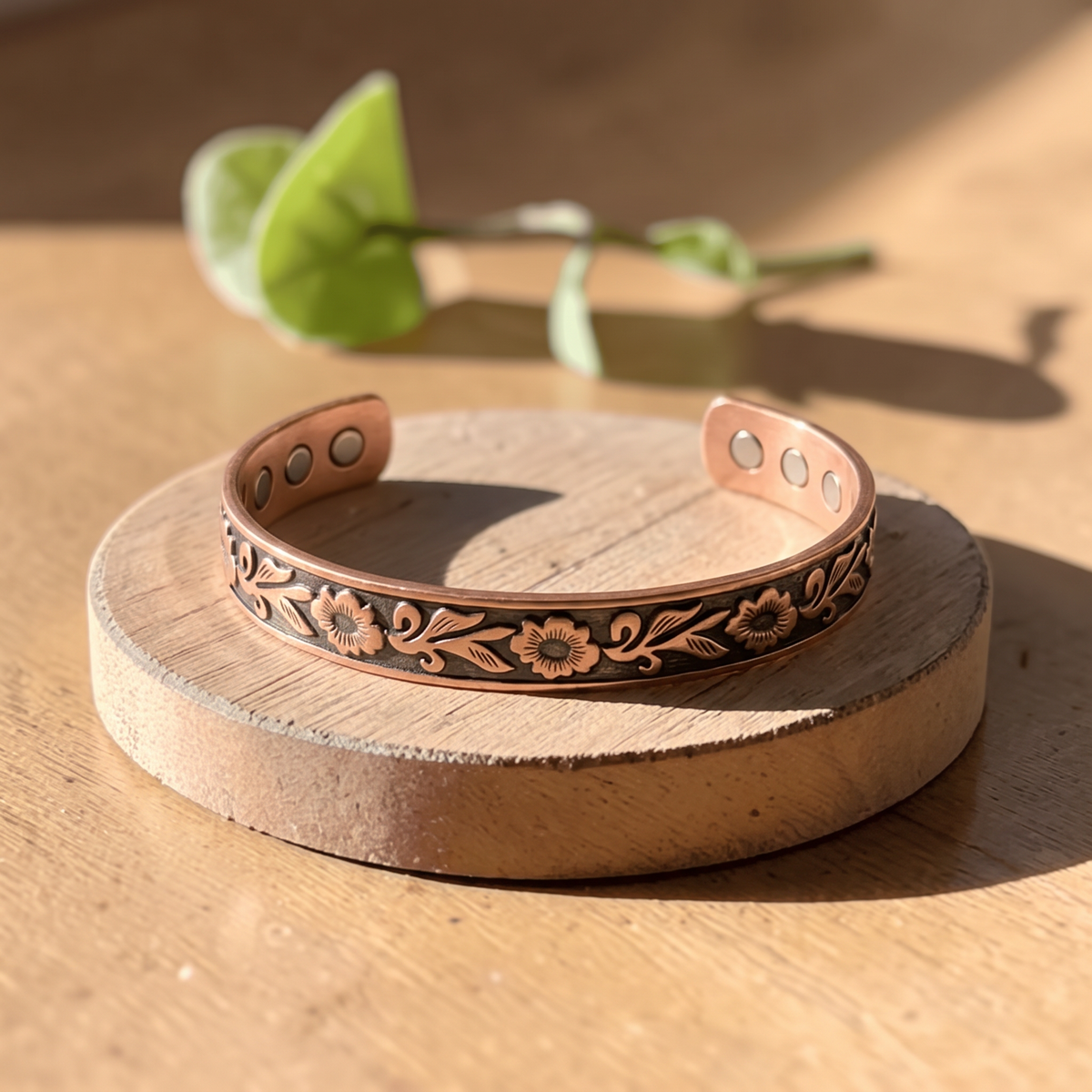 Ella's Eos floral copper cuff on a wooden disc