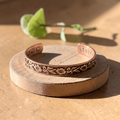 Ella's Eos floral copper cuff on a wooden disc