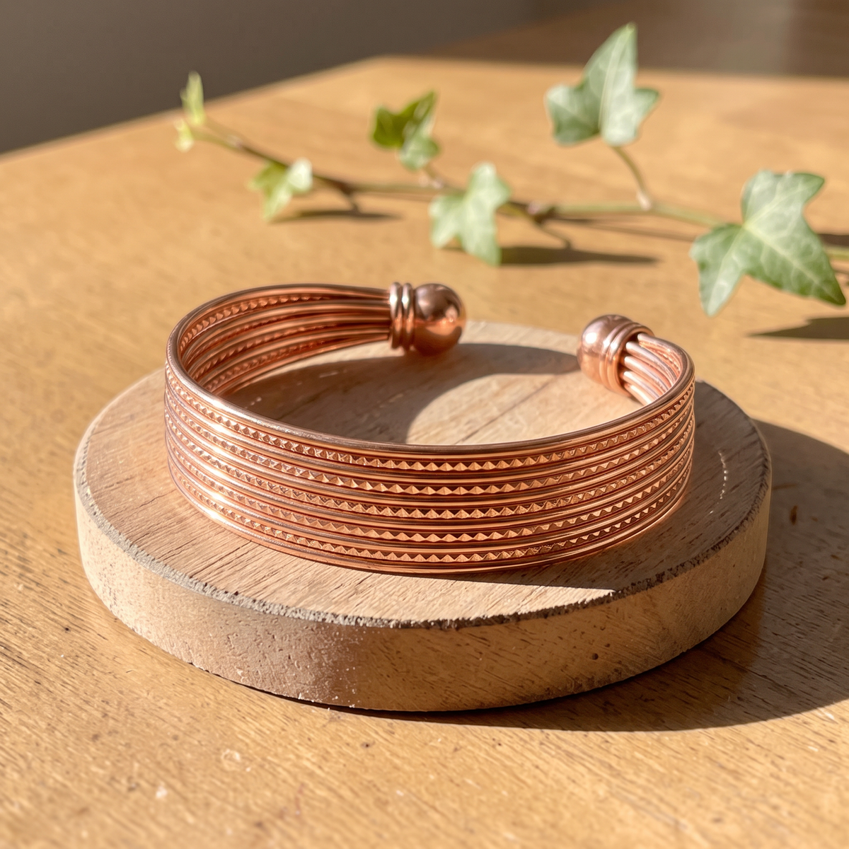 Ella's Rain multi-strand copper cuff on a wooden disc